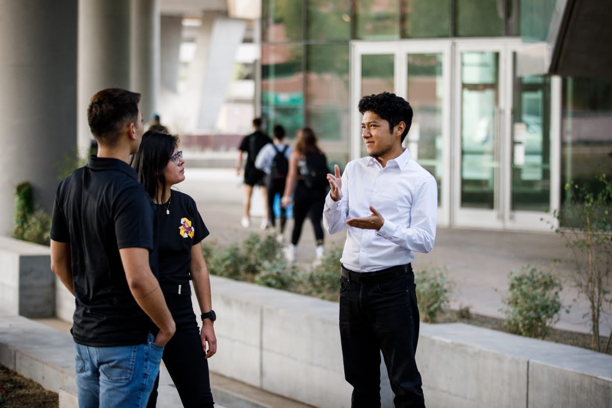A group of people are talking to each other while standing by a building